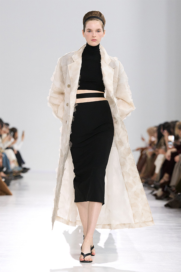 Max Mara Spring/Summer 2026 Fashion Show - Look with light Trench Coat over Turtleneck and black, close-fitting Skirt.